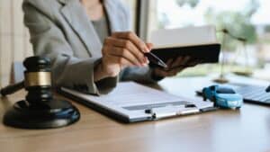 Un abogado firmando un contrato de coche con un mazo y un coche de juguete sobre la mesa, simbolizando el derecho de automoción, el seguro o un acuerdo legal.