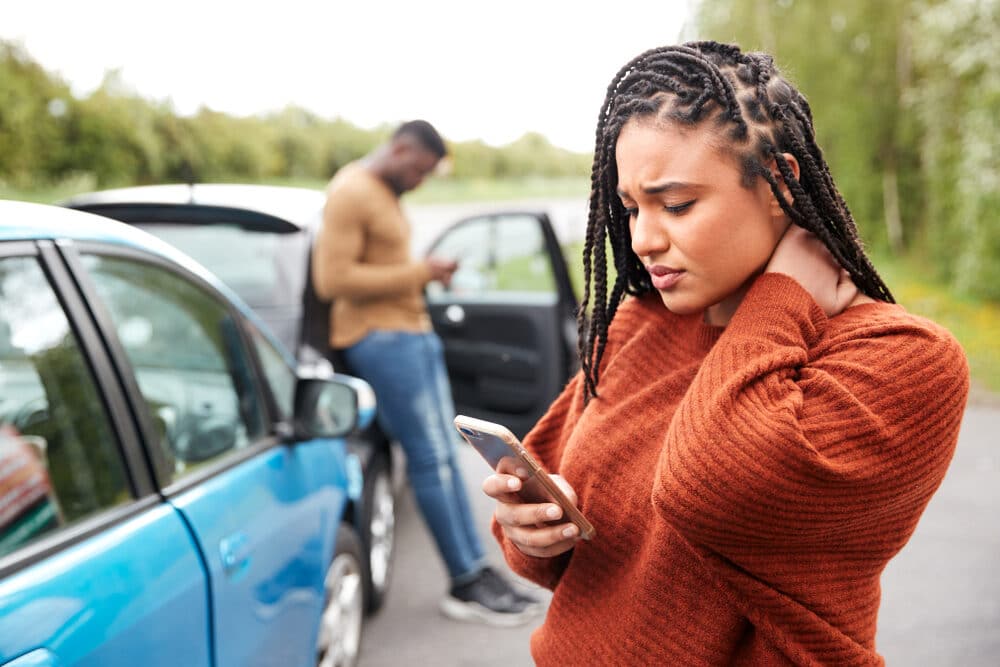 Mujer conductora implicada en un accidente de coche llamando a la compañía de seguros o al servicio de asistencia