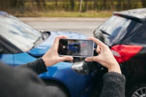 Primer plano de conductora tomando fotos del accidente de tráfico en la carretera con el teléfono móvil para la reclamación del seguro