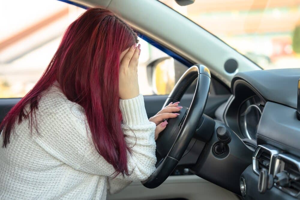 Mujer al volante de un coche, sujetándose la cabeza: sintiéndose mal, accidente