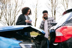 Pareja al lado de la carretera intercambiando detalles del seguro de coche después de un accidente de tráfico