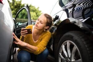 Mujer joven y guapa comprobando el estado de un coche a efectos del seguro, antes de empezar a conducirlo tras alquilarlo en una empresa de alquiler de coches.