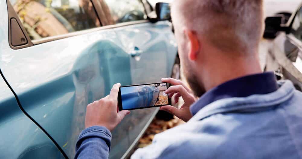 Investigador de seguros captura pruebas de las secuelas de un accidente de tráfico con un smartphone.