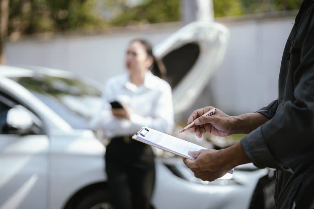 Mujer asiática llama a la compañía de seguros para pedir ayuda tras un accidente de coche