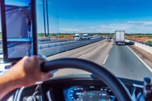 Vista desde la posición de conducción de un camión en una autopista de tres carriles con mucho tráfico.