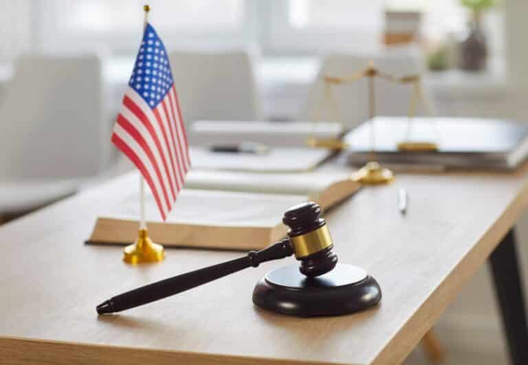 Closeup of modern office interior of judge or lawyer with wooden gavel and american flag on table.