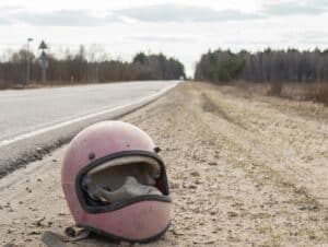 Casco retro de motocicleta tirado junto a la carretera sin cristal después de un accidente.