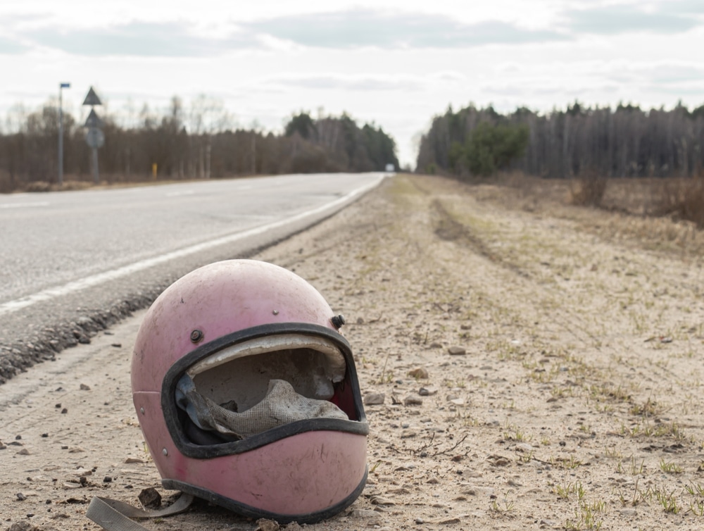 Casco retro de motocicleta tirado junto a la carretera sin cristal después de un accidente.