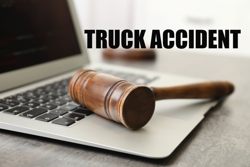 Derecho de accidentes de camión. Portátil y mazo de juez sobre la mesa en interior, primer plano