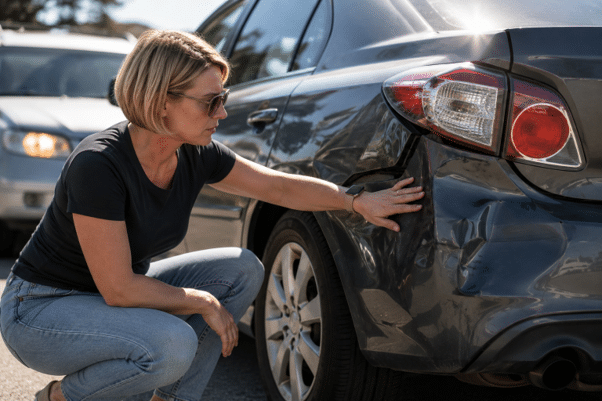 Conductor inspeccionando los daños de una colisión por alcance tras un accidente en Newport Beach.